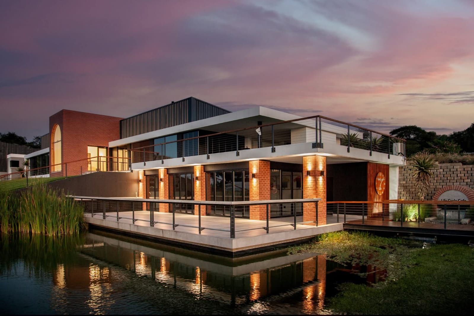 Insect Science office building lit up at dusk, reflected in the pond